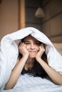 Beautiful bored mixed race woman lies in bed under blanket at home