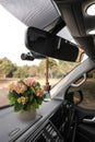 Beautiful bouquet and air freshener hanging on rear view mirror in car