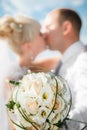 Beautiful bouquet of the bride executed from light beige roses with the wedding kissing couple