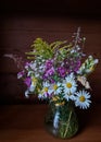 Beautiful bouquet of bright wild flowers on a wooden background in a glass vase Royalty Free Stock Photo