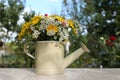 Beautiful bouquet of bright wildflowers in watering can on white wooden table outdoors Royalty Free Stock Photo