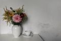 Beautiful bouquet of colorful dahlia, cosmos, solidago flowers. Cup of coffee on table. Blurred old white shabby wall