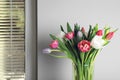 Beautiful bouquet of colorful tulips in glass vase near beige wall at home Royalty Free Stock Photo