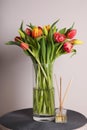 Beautiful bouquet of colorful tulips in glass vase on table against pink background Royalty Free Stock Photo