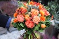 Beautiful bouquet in coral orange colors of roses, tulips, Jatropha multifida, Carthamus tinctorius and other plants in the male