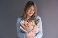 Portrait of a young woman with a bouquet of roses on a gray background. Royalty Free Stock Photo