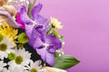 Beautiful bouquet of flowers in lilac wooden basket on purple background. Orchids, chrysanthemums, lilies, chamomiles floral