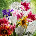 Beautiful bouquet of flowers that are outside the window on the glass of which there are many drops of water