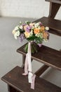 Beautiful bouquet of flowers of roses and lilac stands on a wooden ladder against a white brick wall. Royalty Free Stock Photo