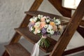 Beautiful bouquet of flowers of roses and lilac stands on a wooden ladder against a white brick wall. Royalty Free Stock Photo