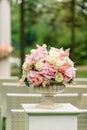 A beautiful bouquet of flowers in a stone vase stands on a column on a green background. Decor for the wedding ceremony Royalty Free Stock Photo