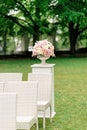 A beautiful bouquet of flowers in a stone vase stands on a column on a green background. Decor for the wedding ceremony Royalty Free Stock Photo