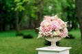 A beautiful bouquet of flowers in a stone vase stands on a column on a green background. Decor for the wedding ceremony Royalty Free Stock Photo