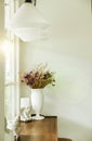 Beautiful Bouquet of Flowers in White Shiny Ceramic Flowerpot on Rustic Wooden Table at The Corner of Luxury White Living Room