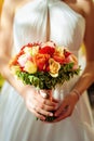 Beautiful bouquet of fresh flowers in the hands of bride in white dress. Wedding flowers close-up Royalty Free Stock Photo