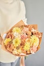 a beautiful bouquet of fresh flowers in the hands of a florist. A gift bouquet in a peach color scheme for any holiday