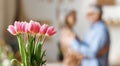 Beautiful bouquet of fresh pink tulips against dancing senior couple in love on blurred background Royalty Free Stock Photo