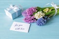 Beautiful bouquet of hyacinth flowers in pink, blue, white, violet colors and blue gift box, card with text For you with love on