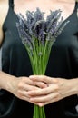 Beautiful bouquet of lavender in female hands. A woman in black holds a bouquet of lavender flowers in front of her Royalty Free Stock Photo