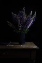 Beautiful bouquet of lupine flowers in a vase on a wooden table on a dark background Royalty Free Stock Photo