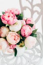 Beautiful bouquet peonies on forged vintage chair in white room