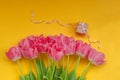 Beautiful bouquet of pink tulips flowers with present box on yellow background. Waiting for spring Royalty Free Stock Photo