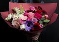 A beautiful bouquet of rare flowers with anemones, ranunculus, carnations, lilac, in the hands of a girl