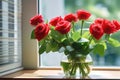 A beautiful bouquet of red blossoming roses in a glass vase against the background of a window Royalty Free Stock Photo