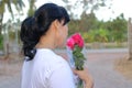 A beautiful bouquet of red roses are held by asian middle aged woman on nature blurred background. Love and romance Valentine`s d