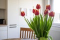 Beautiful bouquet of red-yellow tulips stands in a vase on a wooden table, in a cozy home interior. Royalty Free Stock Photo