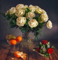 Beautiful bouquet of roses in a crystal jug and a pear with tangerines. Royalty Free Stock Photo