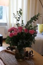 Beautiful bouquet of roses and eucalyptus branches in vase near candles on table at home Royalty Free Stock Photo