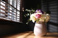 Beautiful bouquet with spring freesia flowers on sunlit wooden table in room Royalty Free Stock Photo