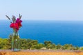 Beautiful bouquet in vase on wooden hand rail against seascape background Royalty Free Stock Photo