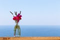 Beautiful bouquet in vase on wooden hand rail against seascape background Royalty Free Stock Photo