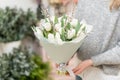 Beautiful bouquet of white tulips flowers in woman hand. the work of the florist at a flower shop. cute lovely girl