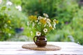 Beautiful bouquet of wildflowers against the background of a summer garden. Flowers in ceramic vase on wicker mat on a white Royalty Free Stock Photo