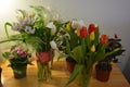 Beautiful bouquets in jars, glass glasses, bottles placed on a yellow wooden table. Royalty Free Stock Photo