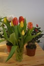 Beautiful bouquets in jars, glass glasses, bottles placed on a yellow wooden table. Royalty Free Stock Photo