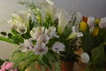 Beautiful bouquets in jars, glass glasses, bottles placed on a yellow wooden table. Royalty Free Stock Photo