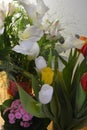 Beautiful bouquets in jars, glass glasses, bottles placed on a yellow wooden table. Royalty Free Stock Photo