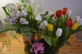 Beautiful bouquets in jars, glass glasses, bottles placed on a yellow wooden table. Royalty Free Stock Photo