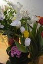 Beautiful bouquets in jars, glass glasses, bottles placed on a yellow wooden table. Royalty Free Stock Photo