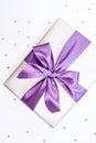 Beautiful box-gift in silver paper with trendy violet ribbon and bow-knot and sprickle stars. Holiday concept