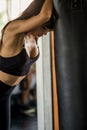 Beautiful boxer young woman tired taking a break from exercise leaning against punching bag in fitness gym .healthy .girl in