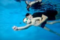 A beautiful boy and a female coach swim under the water with their arms outstretched. They smile and look at the camera Royalty Free Stock Photo