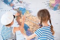 Beautiful boy and a girl in sailor striped shirts measure distance on world map with measuring tape