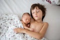 Beautiful boy, hugging with tenderness and care his newborn baby brother at home Royalty Free Stock Photo