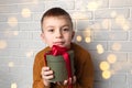 Beautiful boy in a yellow sweater holds a green round gift with a red ribbon Royalty Free Stock Photo