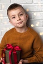 Beautiful boy in a yellow sweater holds a green round gift with a red ribbon Royalty Free Stock Photo